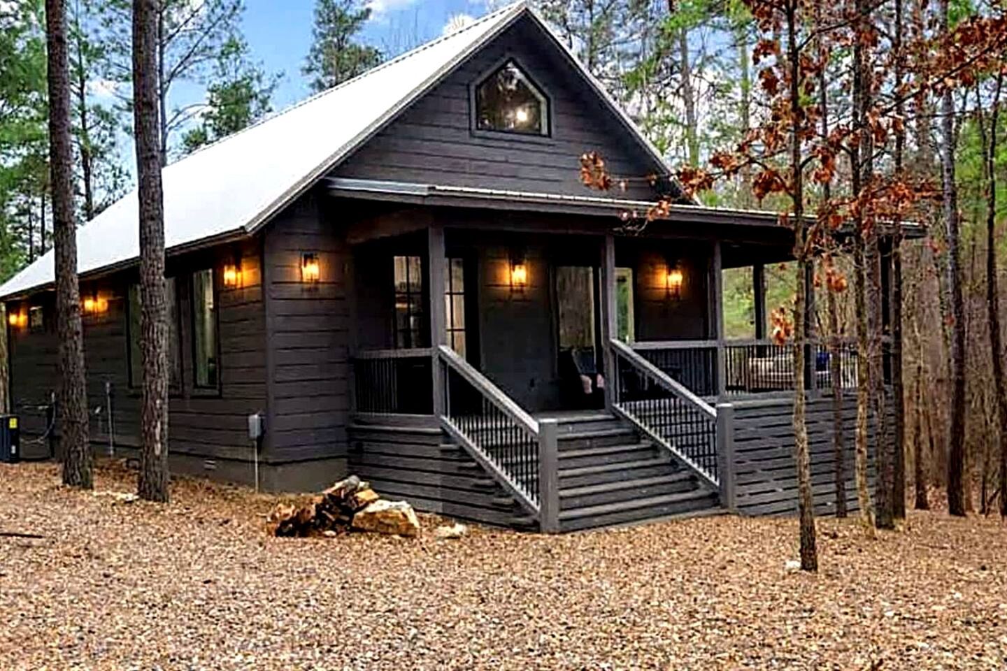 A cabin with a porch, a staircase, and a view of the surrounding forest.