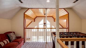 A loft bedroom with a red sofa, a foosball table, and a wooden ceiling.