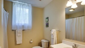 A bathroom with a toilet, sink, mirror, and a window with a curtain. - Family Time in Love, Virginia: Mountain Cabin Getaway (Love)
