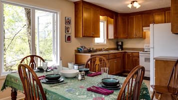 A dining area with wooden chairs, a table set for four, and a kitchen in the background.