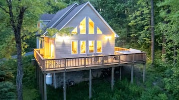 A house with a deck, surrounded by trees.
