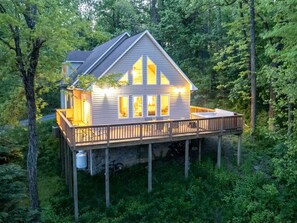 A house with a deck, surrounded by trees.