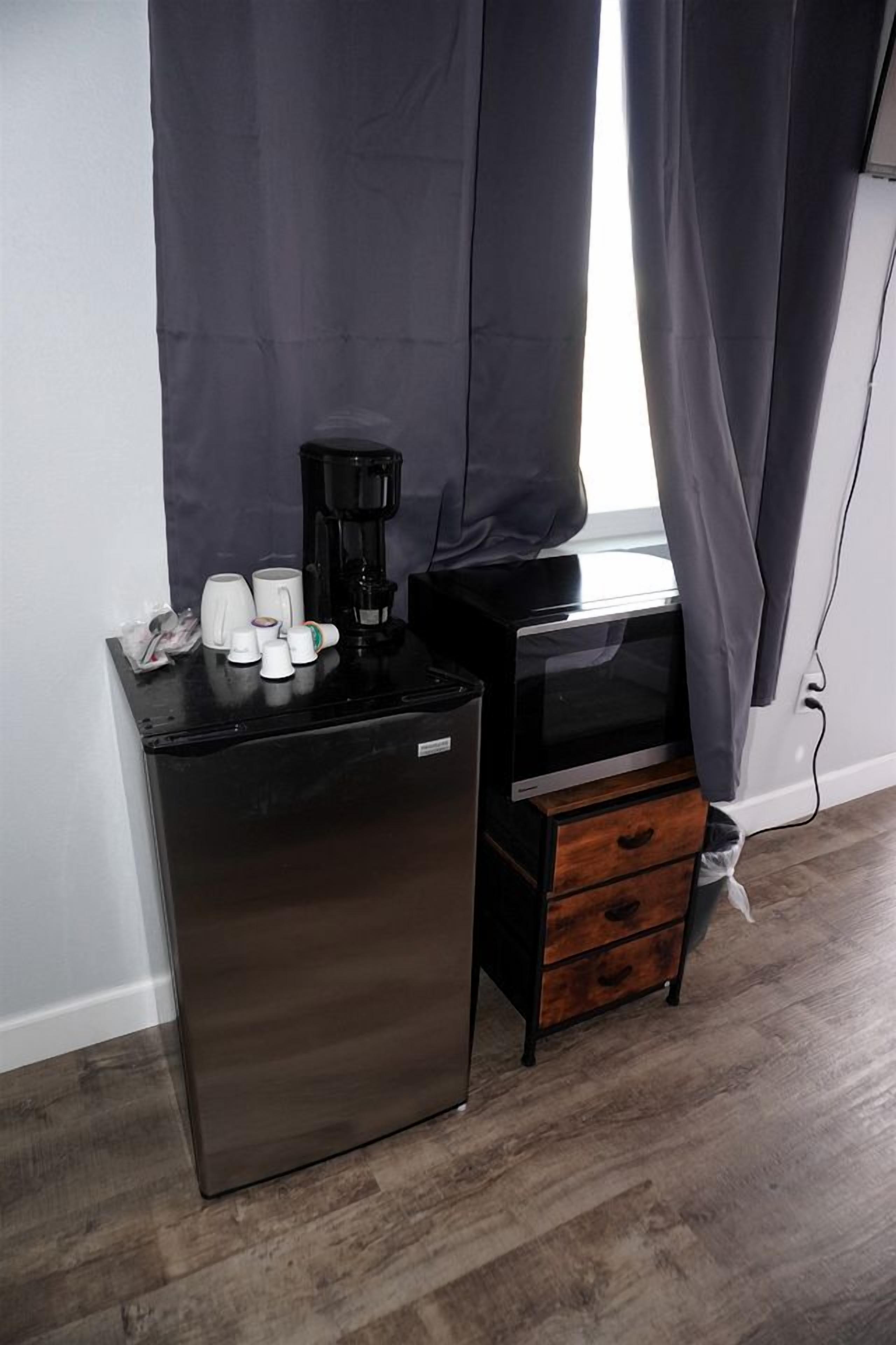 A compact kitchenette with a refrigerator, coffee maker, and microwave.