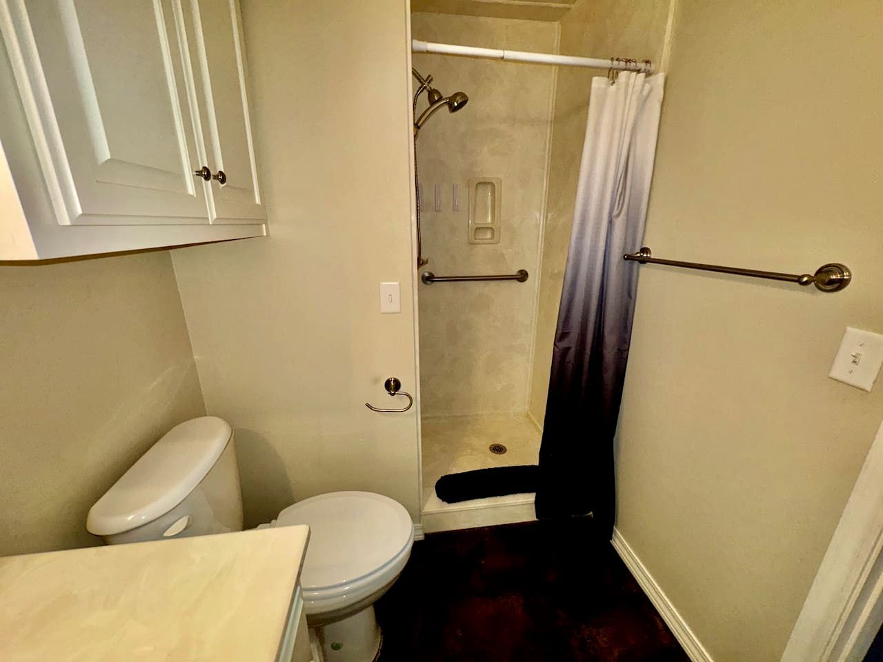 A small bathroom with a toilet, a shower with a curtain, and a towel rack.