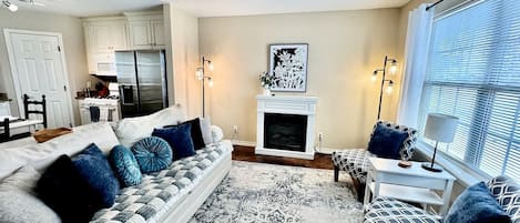A living room with a sofa, a patterned rug, a fireplace, and a ceiling fan.