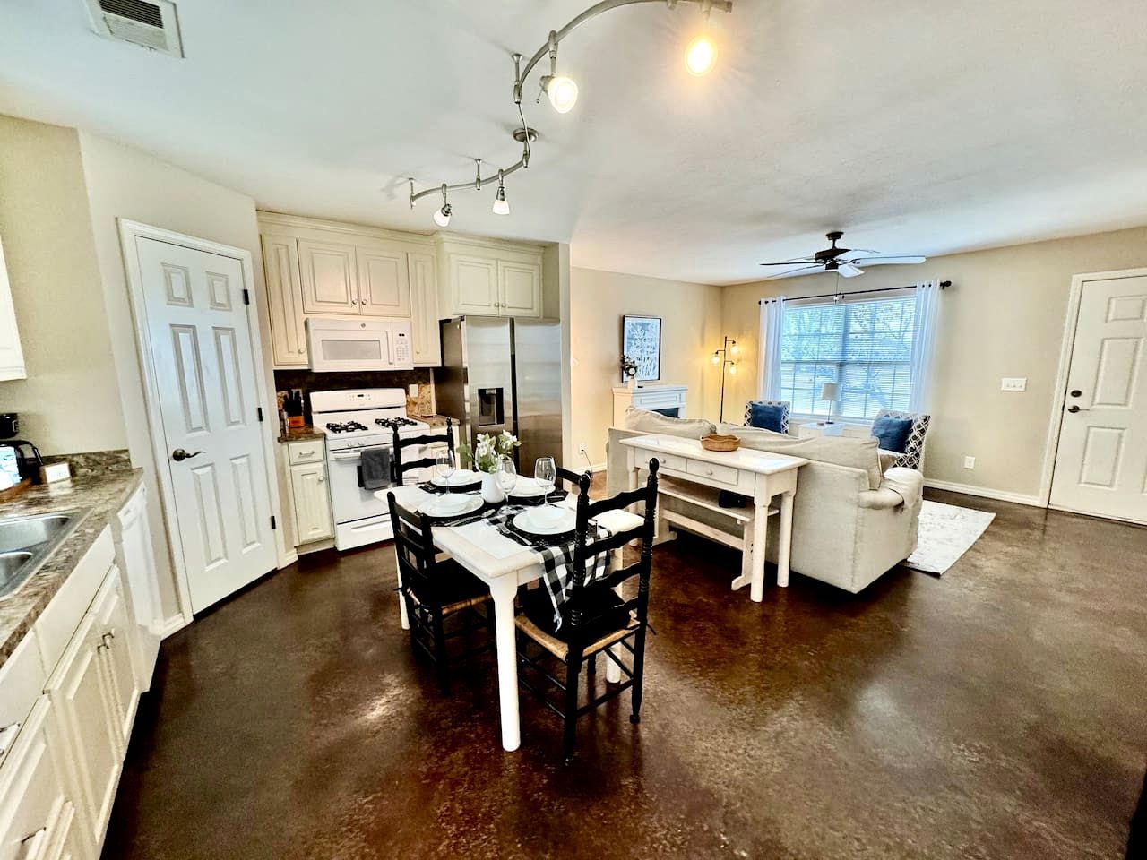 A kitchen with white cabinets, a dining table set for four, and a ceiling fan.