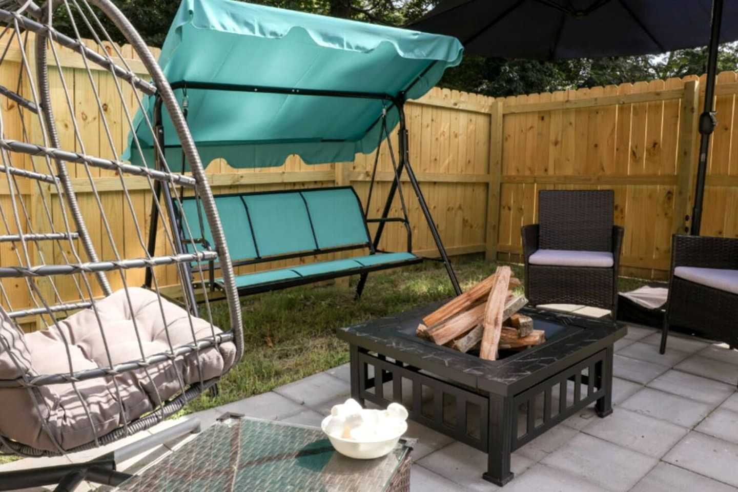 Un patio con una silla mecedora, una mesa con un cuenco y un hogar para fuego.