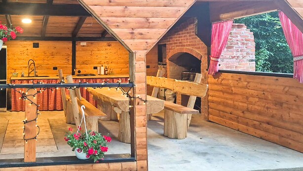 Une cabane en bois rustique comprenant un coin cuisine, une table à manger et une cheminée en briques.