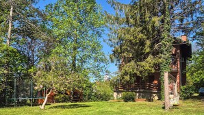 Un chalet rustique doté d’une terrasse en bois, entouré d’une végétation luxuriante et surplombant un ciel d’un bleu éclatant.