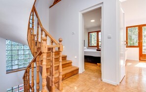 Eine Holztreppe führt zu einem Schlafzimmer mit einem Fenster.