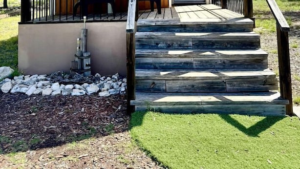 A wooden building with a sign reading 'Wildbills Hideaway,' a porch with chairs, and a set of stairs leading to the entrance. - Rustic Ranch Hideaway Cabin with Stargazing & Sunset Views near Kerrville in Mountain Home, Texas (Mountain Home)