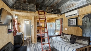 A rustic cabin interior with a wooden ladder, a bed, a desk, and a bathroom. - Rustic Ranch Hideaway Cabin with Stargazing & Sunset Views near Kerrville in Mountain Home, Texas (Mountain Home)