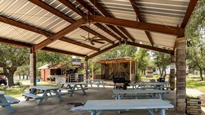 A covered picnic area with tables and a barbecue grill. - Rustic Ranch Hideaway Cabin with Stargazing & Sunset Views near Kerrville in Mountain Home, Texas (Mountain Home)
