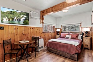 Ein Zimmer mit einem Bett, einem Tisch, Stühlen, einem Fernseher und einem Fenster.