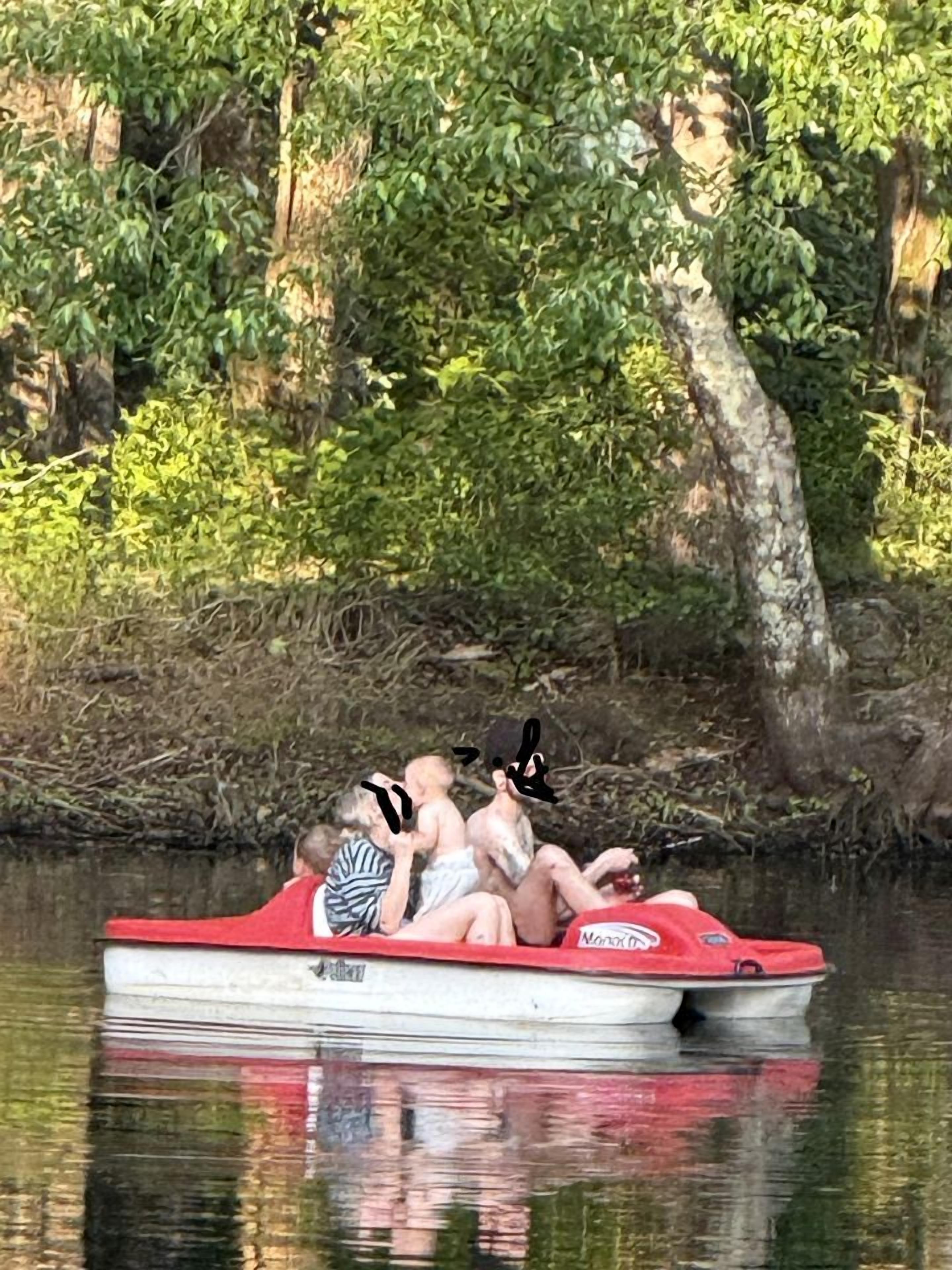 Ein rotes Boot mit Personen, umgeben von Wasser und Grünpflanzen.