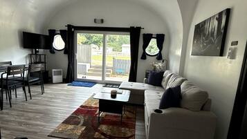Ein kompakter Wohnbereich mit Essbereich, einer Couch, einem Flachbildfernseher und einem großen Fenster.