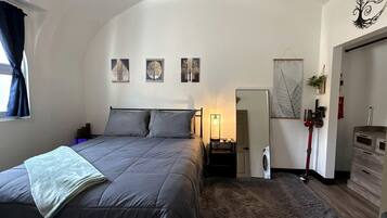 A bedroom with a bed, a nightstand, a dresser, a mirror, and wall art.