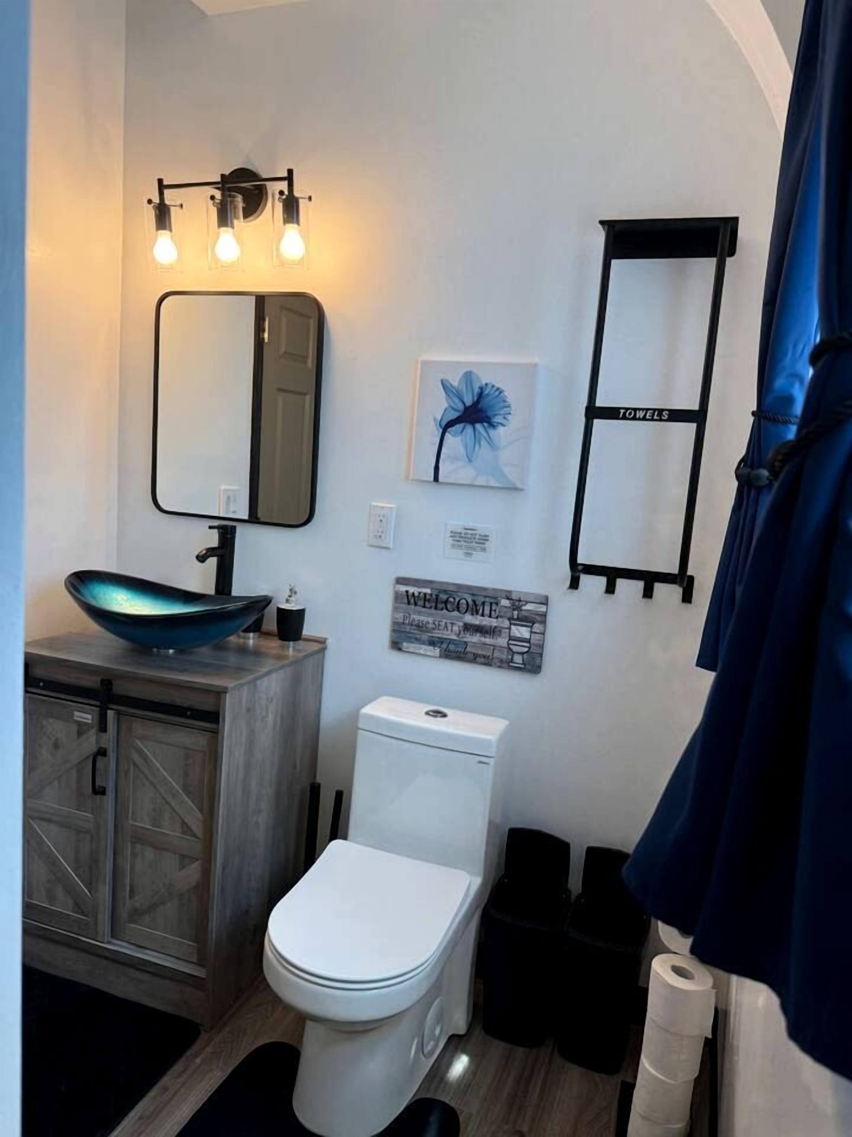 Ein Badezimmer mit einem modernen Waschbecken, einer Toilette, einem Spiegel und einem Handtuchhalter.