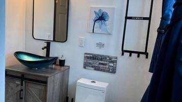 Ein Badezimmer mit einem modernen Waschbecken, einer Toilette, einem Spiegel und einem Handtuchhalter.