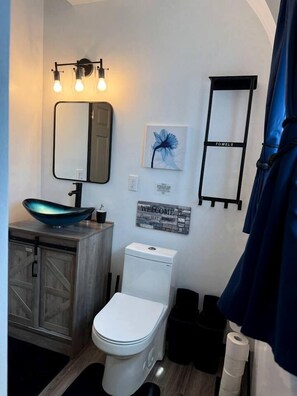 Ein Badezimmer mit einem modernen Waschbecken, einer Toilette, einem Spiegel und einem Handtuchhalter.