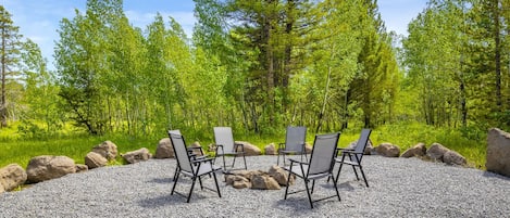 A gravel area with four chairs arranged in a circle, surrounded by rocks and trees.