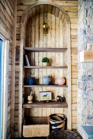 A wooden interior with a stone wall, shelves with various items, and baskets. - Designed Rental with Awesome Indoor Spaces in Idaho (Island Park)