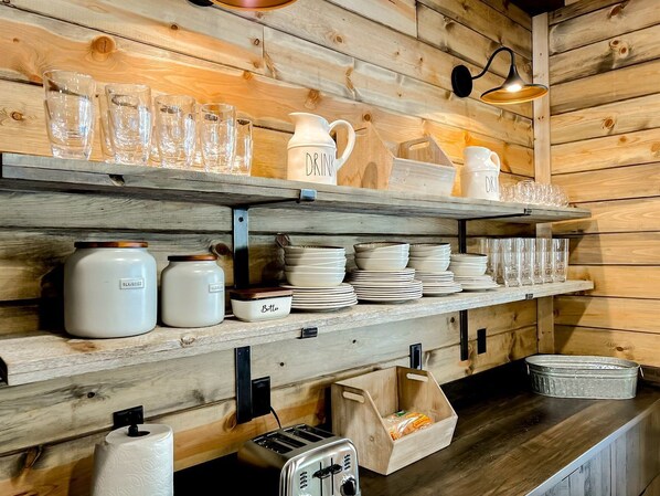A wooden interior with shelves holding glassware, plates, and jars. - Designed Rental with Awesome Indoor Spaces in Idaho (Island Park)