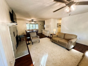 A living room with a beige sofa, patterned armchair, and a ceiling fan.
