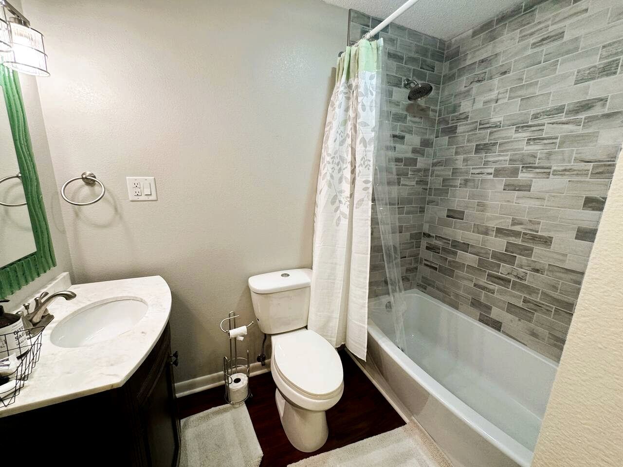 A bathroom with a white sink, toilet, and glass-enclosed shower.