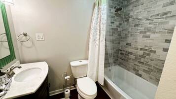 A bathroom with a white sink, toilet, and glass-enclosed shower.