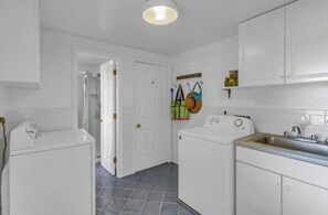 Une cuisine de taille réduite avec des meubles blancs, un lave-linge et un évier.