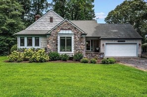A two-story house with a stone facade, a garage, and a well-maintained lawn. - Riverfront Retreat: Hot Tub, Fire Pit, Private Dock & Screened Porch (Lancaster)