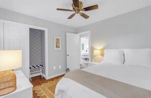 A bedroom with a bed, a ceiling fan, a nightstand with a lamp, and a door leading to another room. - Riverfront Retreat: Hot Tub, Fire Pit, Private Dock & Screened Porch (Lancaster)
