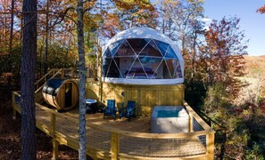 Uma estrutura em forma de cúpula geodésica com terraço, assentos e banheira de hidromassagem.
