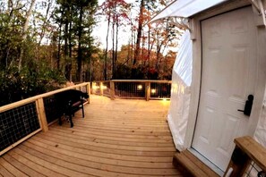 A wooden deck with a railing, a bench, and a door. - Luxury Geodome with Sauna, Hot Tub & Mountain Views near Pisgah National Forest, North Carolina (Balsam Grove)