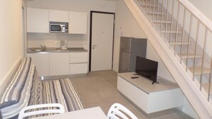 Una cocina compacta con microondas, refrigerador y comedor con mesa y sillas.