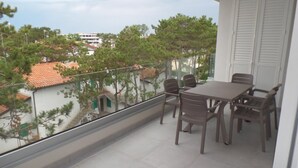Un balcón con mesa y sillas, con vistas a una zona residencial con árboles y edificios.