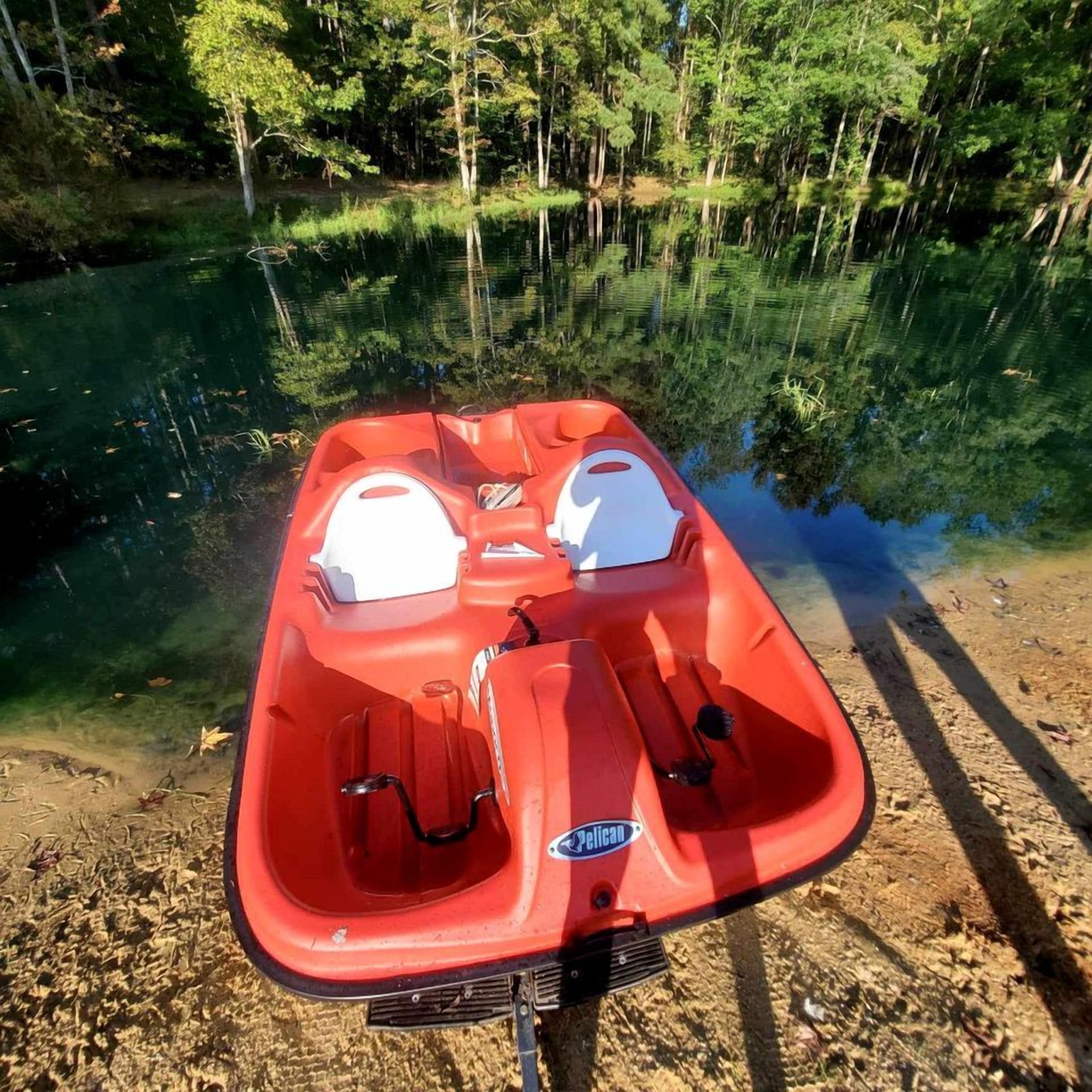 A red inflatable boat with two white helmets, a brand logo, and a water jet.