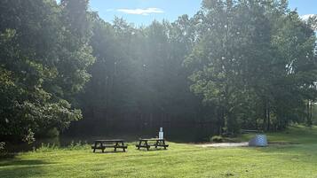A picnic area with two picnic tables and a sign, surrounded by trees and grass.