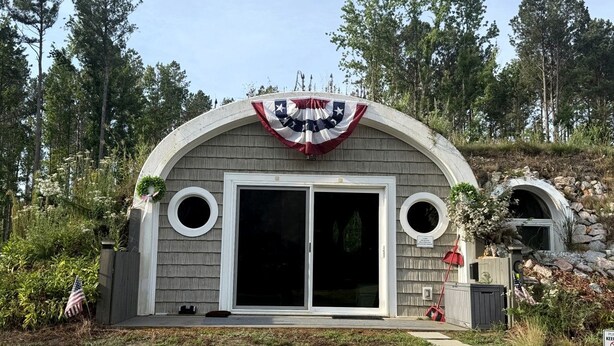 A house with a curved roof, a large sliding glass door, and a flag.