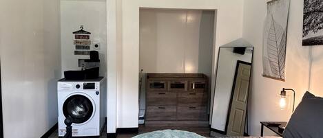 Un dormitorio con lavadora, cama, cómoda y espejo.
