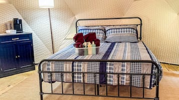 Un lit simple avec un cadre en métal, un matelas matelassé et une lampe de chevet.