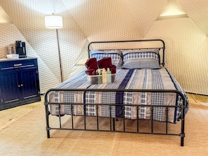 A single bed with a metal frame, a quilted mattress, and a bedside lamp.