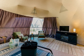 Habitación tipo tienda de campaña con televisión, zona de estar y chimenea.