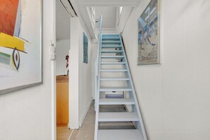 En smal hall med en blå trappa som leder upp till ett rum.