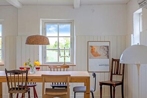 En matplats med ett träbord, stolar, en ljusstake och ett inramat konstverk på väggen.