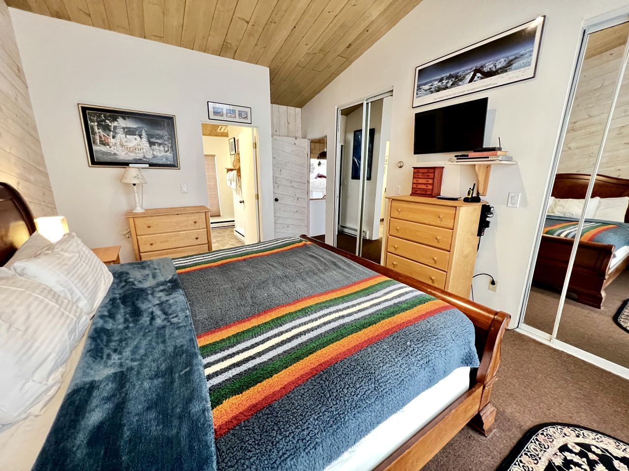 Une chambre à coucher avec un lit, une commode, un miroir et un téléviseur.
