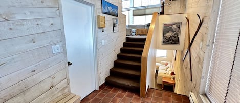A wooden interior with a staircase, a door, and a window.