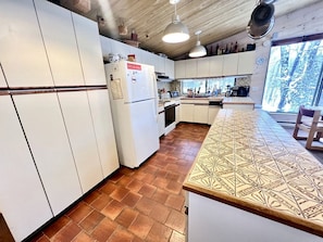A kitchen with white cabinets, a patterned countertop, and a view of trees through a window.