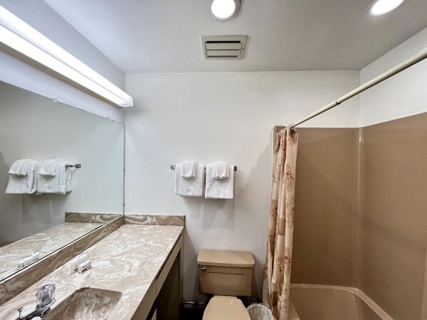 A bathroom with a marble vanity, a toilet, a shower with a curtain, and two towels hanging on the wall.